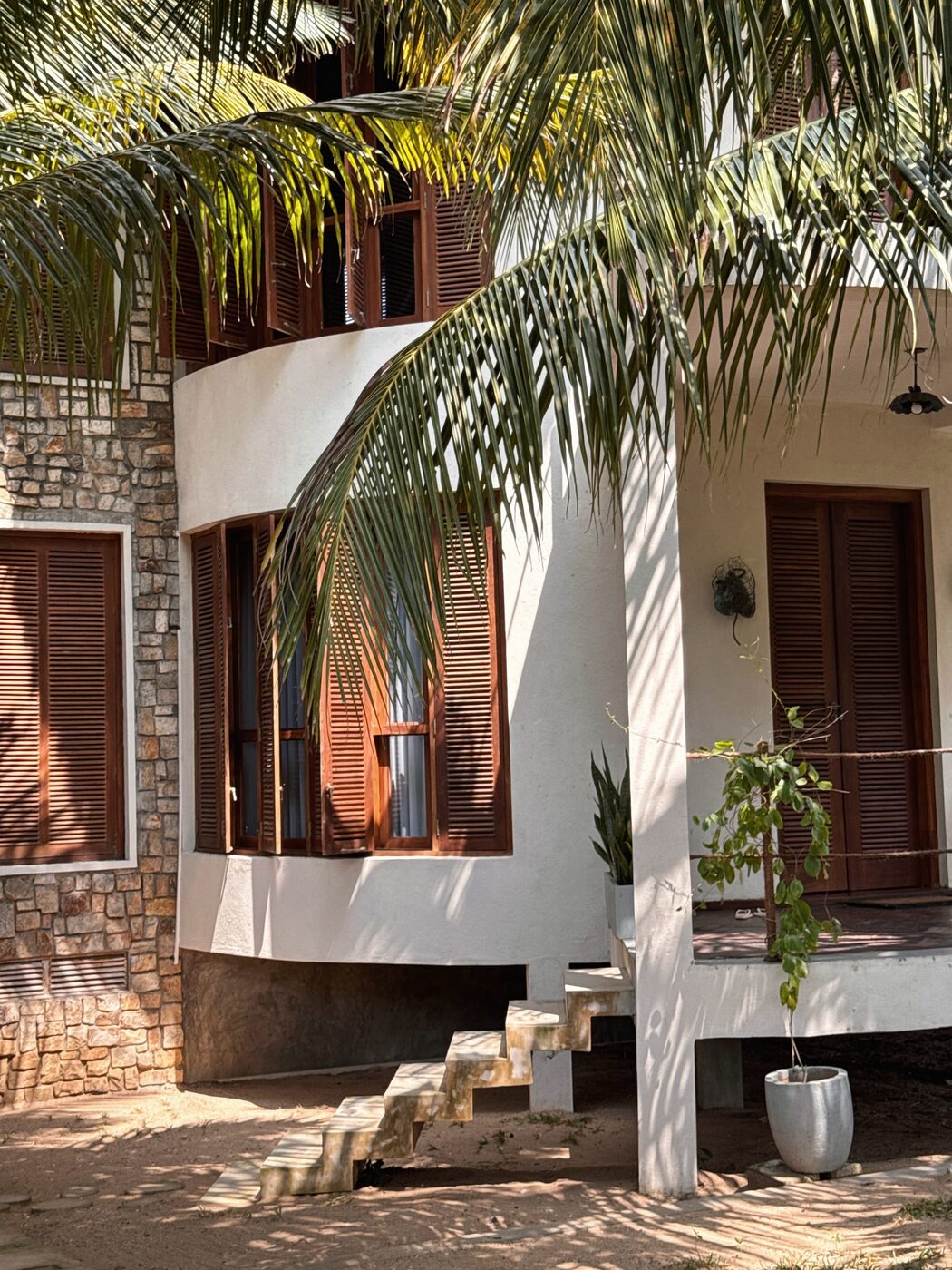 Whitewashed villa with wooden shutters under palm fronds